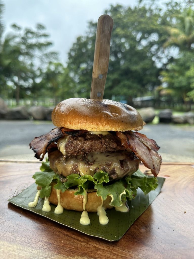 Hamburguesa doble con tortas Black Angus y tocino sobre hoja de plátano
